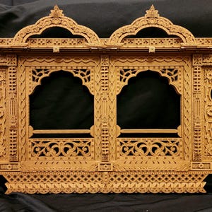 May include: A detailed, wooden decorative window frame with intricate carvings. The frame features two arched openings, ornate floral and geometric patterns, and a warm, natural wood tone. The design is symmetrical and includes decorative elements.