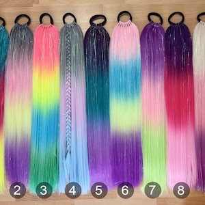 May include: Nine colorful hair extensions with black elastic bands. The extensions feature a variety of vibrant, blended colors, including pink, purple, blue, green, and yellow. Each extension is numbered from one to nine.