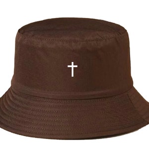 May include: A brown bucket hat with a white cross embroidered on the front.
