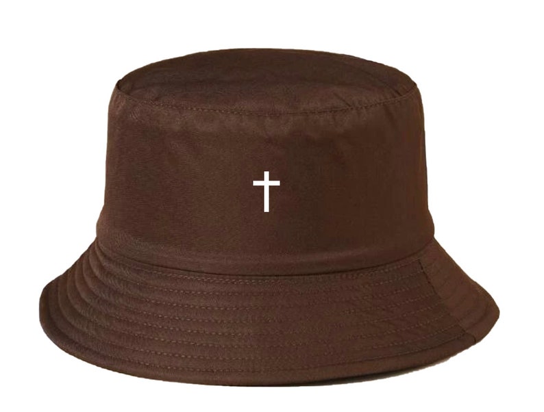 May include: A brown bucket hat with a white cross embroidered on the front.