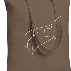 May include: A brown canvas tote bag with white outline of a hand drawing on the front.
