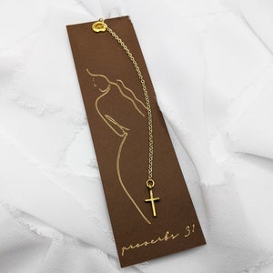 May include: A brown bookmark with a gold chain and a small gold cross charm. The bookmark has a gold outline of a woman and the text "proverbs 3!"