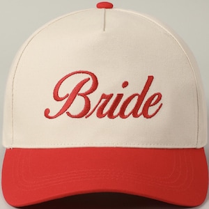 May include: A white and red baseball cap with the word "Bride" embroidered in red on the front.