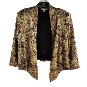 May include: A gold and brown sequined jacket with a black interior. The jacket has a paisley pattern and a draped, open front design. The jacket is hanging on a clear hanger.