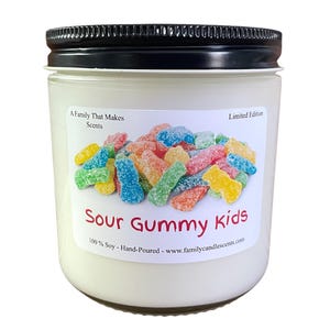Pode incluir: Um frasco de vela branco com uma tampa preta. O rótulo diz "Sour Gummy Kids" e apresenta uma imagem colorida de doces de goma. O rótulo também diz "A Family That Makes Scents", "Edição limitada", "100% Soja - Feito à mão", e "www.familycandlescents.com".