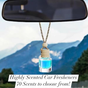 May include: A blue glass car air freshener hanging from the rear view mirror of a car. The air freshener is on a beige string and has a wooden cap. The text "Highly Scented Car Fresheners 70 Scents to choose from!" is visible at the bottom of the image.