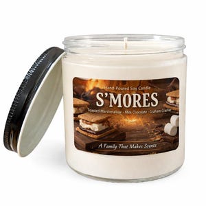 May include: A clear glass jar candle with a black lid. The candle has a white wax interior and a label that reads "S'MORES" with the scent description. The label also says "Hand-Poured Soy Candle" and "A Family That Makes Scents."