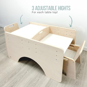 May include: A wooden table and chair set with three adjustable heights. The table has a white top and a cutout for a child to sit in. The chair is also made of wood and has a cutout for a child to sit in. The table and chair are both unfinished and have a natural wood color.