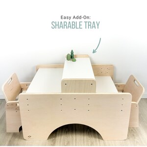 May include: A wooden table with two chairs and a removable tray. The table is light brown and has a white surface. The tray is labeled "Sharable Tray".