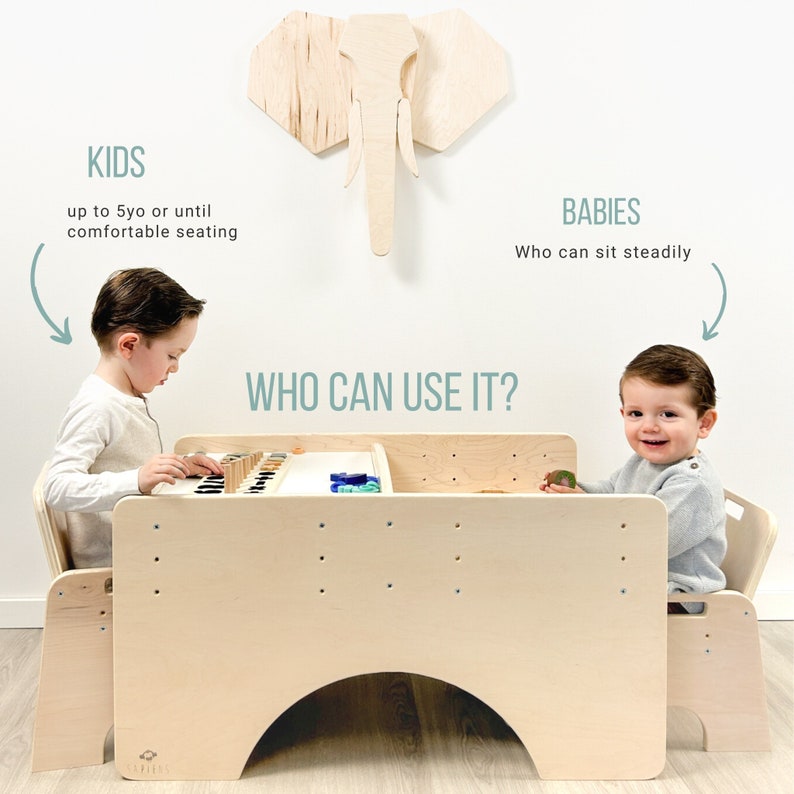 May include: A wooden play table with two chairs, designed for children. The table has a built-in activity center with colorful blocks and a white surface. The text "WHO CAN USE IT?" is written above the table. The text "KIDS up to 5yo or until comfortable seating" is written on the left side of the image. The text "BABIES Who can sit steadily" is written on the right side of the image.
