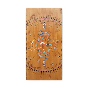 May include: A wooden panel with a painted Native American design. The design features a circle with horses, a crescent moon, and other symbols. The circle is surrounded by a border of spikes and a row of dragonflies.