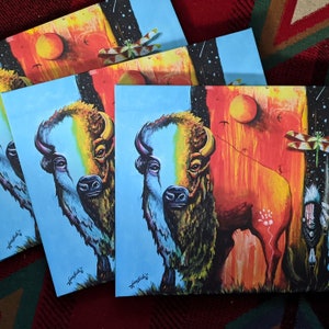 May include: A colorful painting of a bison with a blue and white body and a red and yellow background. The bison is standing in a field with a dragonfly flying above it. The painting is signed "Hoskie" in the bottom right corner.