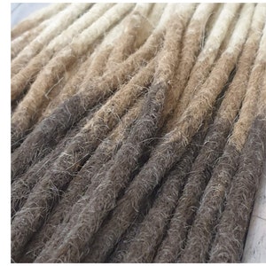 Peut inclure: Gros plan sur un paquet de dreadlocks synthétiques avec un dégradé de couleur brun clair à brun foncé.