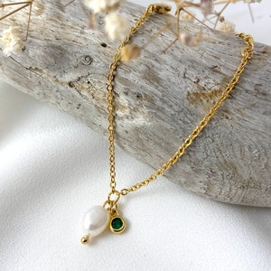 May include: A gold chain bracelet with a pearl and a green gemstone charm.