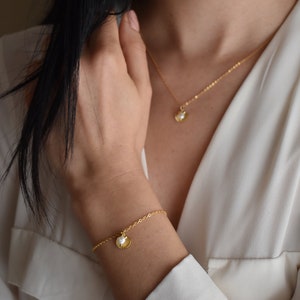 Handmade and dainty jewelry made in Montreal by Piper & Pearl Jewelry. Feminine, modern and delicate, perfect for a gift for her. Collections of costume, vermeil and fine jewelry. Seashell and pearl gold charm bracelet with beachy and boho vibes.