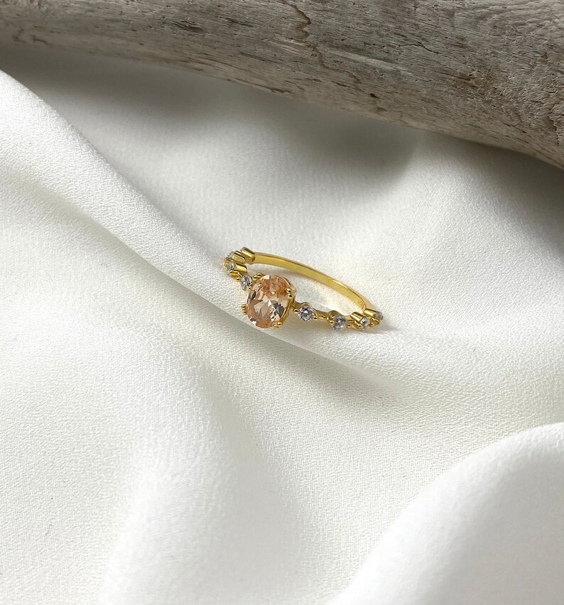 Handmade and dainty jewelry made in Montreal by Piper & Pearl Jewelry. Feminine, modern and delicate, perfect for a gift for her. Collections of costume, vermeil and fine jewelry. Rose pink oval cut pave promise ring on a gold band.