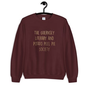 May include: Burgundy sweatshirt with the text "The Guernsey Literary and Potato Peel Pie Society" printed in gold.