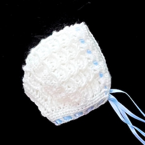 May include: White crocheted baby bonnet with blue ribbon ties. The bonnet has a delicate lace pattern and is trimmed with blue ribbon.