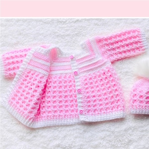May include: A pink and white crocheted baby cardigan and hat set. The cardigan has a button closure and the hat has a white pom-pom.