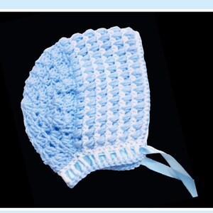 May include: A blue and white crocheted baby bonnet with a white ribbon tie.
