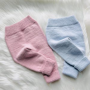 Puede incluir: Un par de pantalones de punto en color rosa pastel suave y un par de pantalones de punto en color azul bebé claro. Ambas prendas cuentan con una cintura elástica acanalada y puños acanalados en los tobillos, con una textura de punto liso.