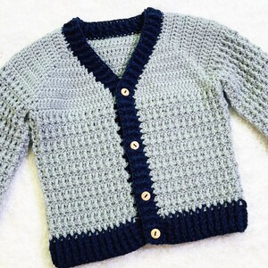 May include: A gray and navy blue crocheted cardigan with wooden buttons.