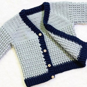 May include: A gray crocheted cardigan with a navy blue trim and wooden buttons.