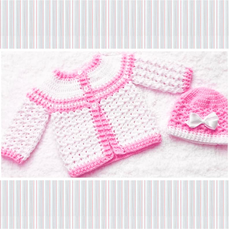 Puede incluir: Un conjunto de cardigan y gorro de beb&eacute; de ganchillo rosa y blanco. El cardigan tiene cierre de bot&oacute;n y el gorro tiene un lazo blanco.