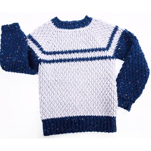May include: A crocheted sweater with long sleeves in a light gray color with navy blue stripes and navy blue sleeves with flecks of color.