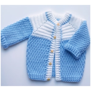 May include: A blue and white knitted cardigan with a button closure. The cardigan has a textured pattern and a white trim around the edges.