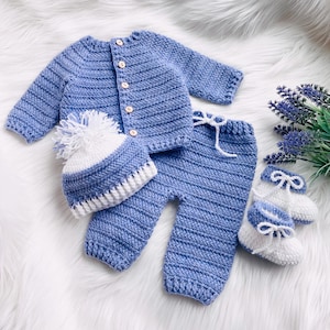 May include: A blue crocheted baby outfit set with a matching hat and booties. The set is made of soft yarn and features a white trim.