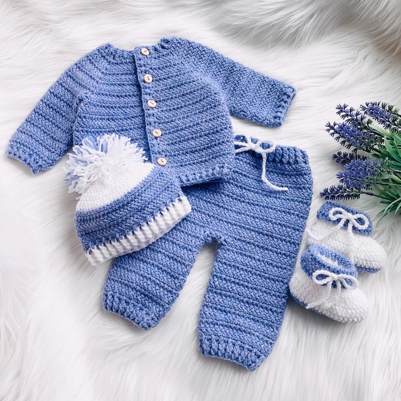 May include: A blue crocheted baby outfit set with a matching hat and booties. The set is made of soft yarn and features a white trim.