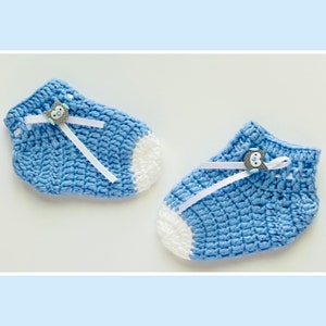 May include: A pair of blue crocheted baby booties with white trim and a small owl button on each bootie.