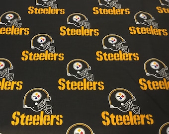 May include: Black fabric with a repeating pattern of yellow and white Pittsburgh Steelers football helmets and the word "Steelers" in yellow stencil font. The helmets have a black shell, a yellow stripe, and a logo.