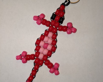 Lagarto con cuentas rojas y rosas