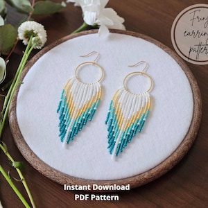 May include: A pair of handmade fringe earrings with gold-colored hoops. The earrings feature a pattern of white, yellow, and teal beads, arranged in a cascading design. The image also includes the text "Fringe earrings pattern" and "Instant Download PDF Pattern".