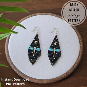 Peut inclure: Paire de boucles d'oreilles en perles noires faites à la main avec un motif de libellule, une lune et des étoiles. Les boucles d'oreilles ont des crochets dorés et des accents turquoise et dorés. Le texte "Brick Stitch + Fringe Pattern" et "Instant Download PDF Pattern" est également présent.