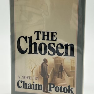 May include: A hardcover book titled "THE Chosen" by Chaim Potok. The cover features a muted color palette with an illustration of two men near a building. The title is in large, bold black letters.