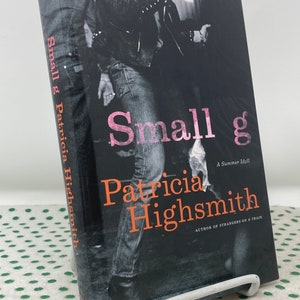 May include: Book cover with a black and white photo of a person wearing a leather jacket and jeans. The title of the book is "Small g" by Patricia Highsmith. The subtitle is "A Summer Idyll".