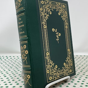 Könnte beinhalten: Ein grünes Hardcover-Buch mit goldenen Lettern und einem floralen Design auf dem Einband. Der Titel des Buches lautet "The End of Obscenity" von Henry Miller.