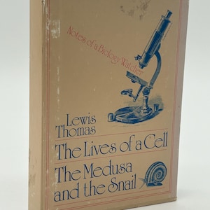 Puede incluir: Un libro antiguo titulado "The Lives of a Cell" de Lewis Thomas. La portada es de color beige con bordes rojos y presenta una ilustración azul de un microscopio y un caracol. También se ve el texto "Notes of a Biology Watcher".