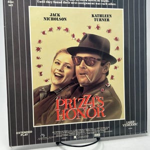 Puede incluir: Un videodisco láser vintage de la película "El honor de los Prizzi" con Jack Nicholson y Kathleen Turner. La portada tiene un fondo beige con el título de la película en rojo y una foto de los actores. El disco es un set de 2 discos.