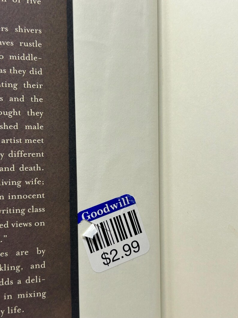 Puede incluir: Un libro con una p&aacute;gina blanca y una p&aacute;gina marr&oacute;n. Una pegatina azul y blanca de Goodwill est&aacute; adherida al libro. La pegatina tiene un c&oacute;digo de barras y el texto "Goodwill" y "$2.99".