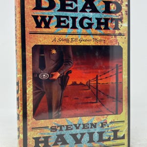 May include: A hardback book titled "DEAD WEIGHT" with a Sheriff Bill Gastner Mystery. The cover shows a sheriff in uniform and a desert scene. The author's name, STEVEN F. HAVILL, is also displayed.