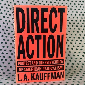May include: A bright orange book cover with the title "DIRECT ACTION" in large black letters. The subtitle is "Protest and the Reinvention of American Radicalism" in smaller black letters. The author's name, "L.A. KAUFFMAN", is printed in black at the bottom of the cover.