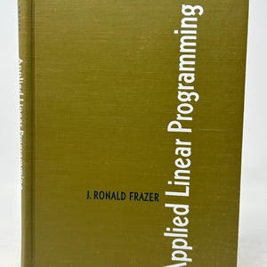 May include: A hardcover book with a textured, olive-green cover. The title "Applied Linear Programming" is printed vertically in white, with the author's name, J. Ronald Frazer, below. The book's spine also has text.