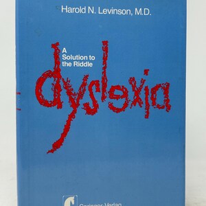 May include: A blue book titled "A Solution to the Riddle of Dyslexia" by Harold N. Levinson, M.D. The title "dyslexia" is in large, red, stylized font. The publisher is Springer-Verlag, with locations in New York, Heidelberg, and Berlin.