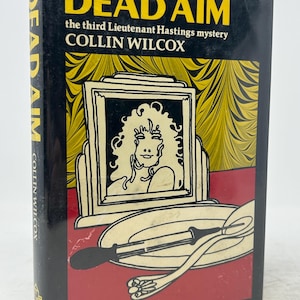 Puede incluir: Un libro de bolsillo vintage titulado "DEAD AIM" de Collin Wilcox. La portada presenta un diseño en negro y amarillo con una ilustración de un retrato enmarcado y un plato con utensilios. El libro es parte de la serie Lieutenant Hastings.