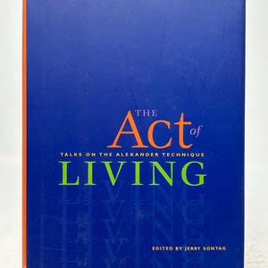 May include: A hardcover book titled "The Act of Living" by Walter Carrington. The cover is a deep blue with the title in large green letters and the word "Act" in orange. The book is about the Alexander Technique.