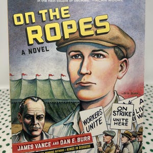 May include: A book cover featuring a graphic illustration of a man wearing a cap and a white shirt. The title of the book is "On the Ropes: A Novel" by James Vance and Dan E. Burr. The cover also shows a group of people holding signs that read "Workers Unite" and "On Strike Unite Here".